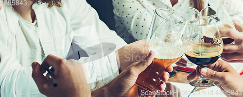 Image of Hands of young friends, colleagues during beer drinking, having fun, laughting and celebrating together. Flyer with copyspace