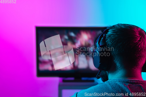 Image of Back view shot of professional gamer playing online video game on his personal computer.