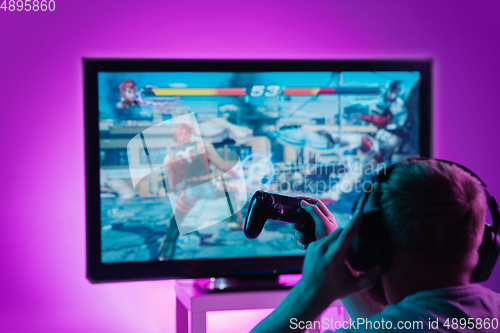 Image of Back view shot of professional gamer playing online video game on his personal computer.