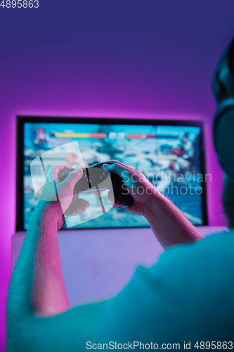 Image of Back view shot of professional gamer playing online video game on his personal computer.