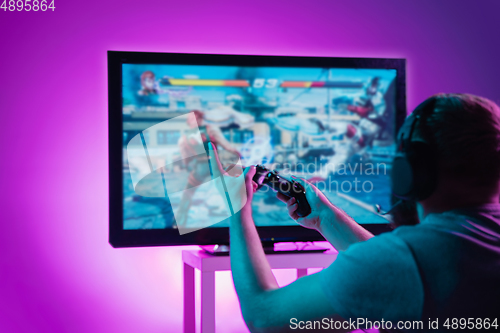 Image of Back view shot of professional gamer playing online video game on his personal computer.