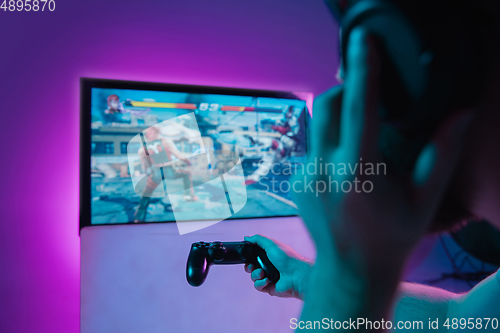 Image of Back view shot of professional gamer playing online video game on his personal computer.