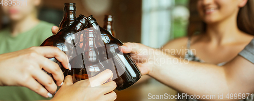 Image of Hands of young friends, colleagues during beer drinking, having fun, laughting and celebrating together. Flyer with copyspace