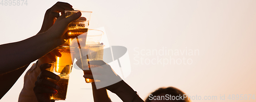 Image of Hands of young friends, colleagues during beer drinking, having fun, laughting and celebrating together. Flyer with copyspace