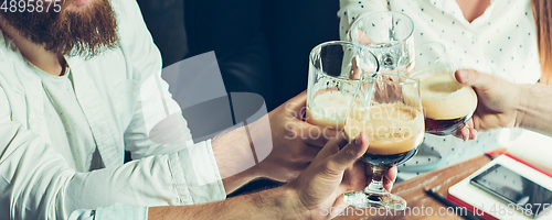 Image of Hands of young friends, colleagues during beer drinking, having fun, laughting and celebrating together. Flyer with copyspace