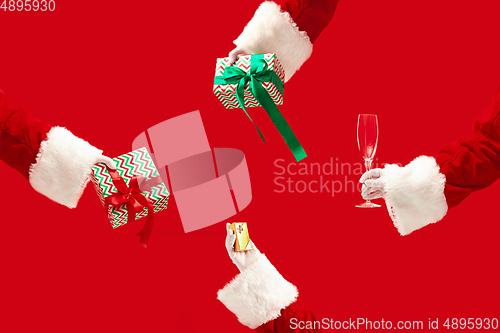 Image of The hands of Santa Claus holding a gifts on red background with copyspace. New Year, Christmas, winter, holiday, celebration, gift concept