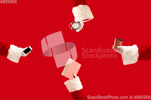 Image of The hands of Santa Claus holding a gifts on red background with copyspace. New Year, Christmas, winter, holiday, celebration, gift concept