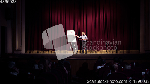 Image of Male caucasian speaker giving presentation in hall at university or business centre workshop