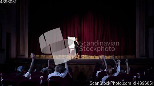 Image of Female caucasian speaker giving presentation in hall at university or business centre workshop