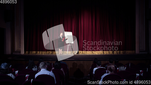Image of Female caucasian speaker giving presentation in hall at university or business centre workshop