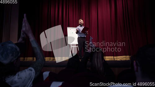 Image of Male caucasian speaker giving presentation in hall at university or business centre workshop