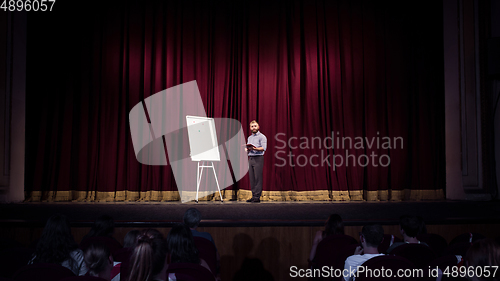 Image of Male caucasian speaker giving presentation in hall at university or business centre workshop