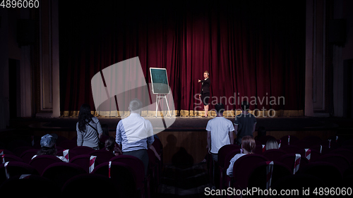 Image of Female caucasian speaker giving presentation in hall at university or business centre workshop