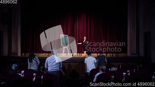 Image of Female caucasian speaker giving presentation in hall at university or business centre workshop
