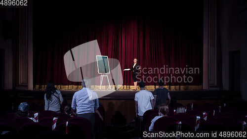 Image of Female caucasian speaker giving presentation in hall at university or business centre workshop