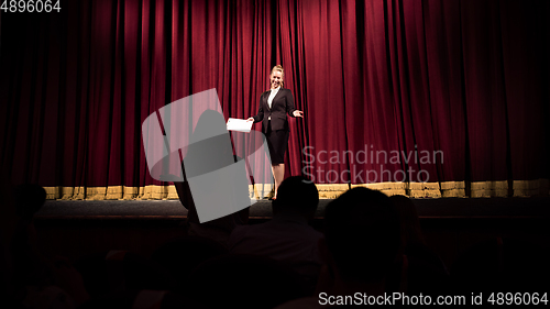 Image of Female caucasian speaker giving presentation in hall at university or business centre workshop