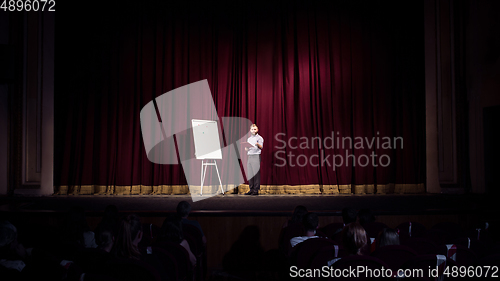 Image of Male caucasian speaker giving presentation in hall at university or business centre workshop