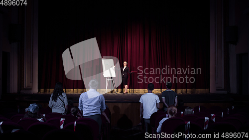 Image of Female caucasian speaker giving presentation in hall at university or business centre workshop