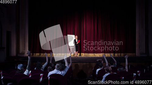 Image of Female caucasian speaker giving presentation in hall at university or business centre workshop