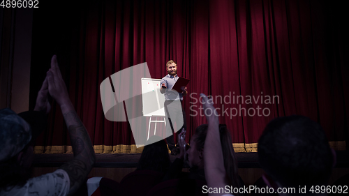 Image of Male caucasian speaker giving presentation in hall at university or business centre workshop