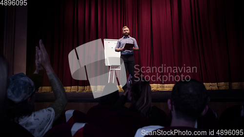 Image of Male caucasian speaker giving presentation in hall at university or business centre workshop