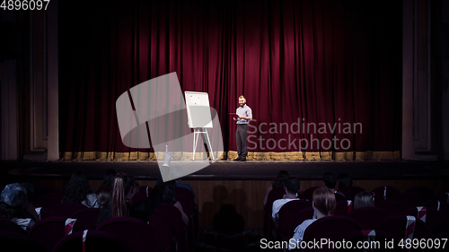 Image of Male caucasian speaker giving presentation in hall at university or business centre workshop