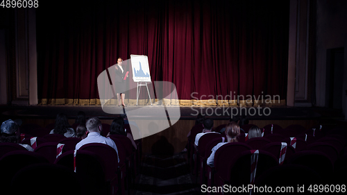 Image of Female caucasian speaker giving presentation in hall at university or business centre workshop