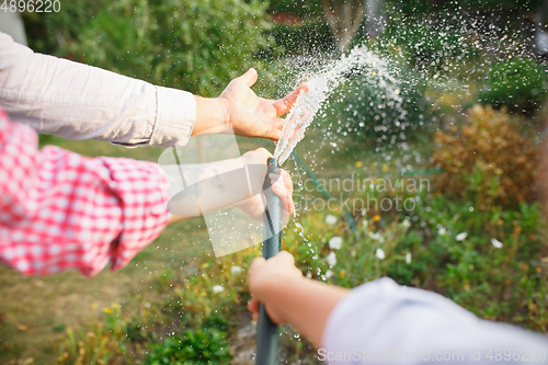 Image of Happy family during watering plants in a garden outdoors. Love, family, lifestyle, harvest concept.