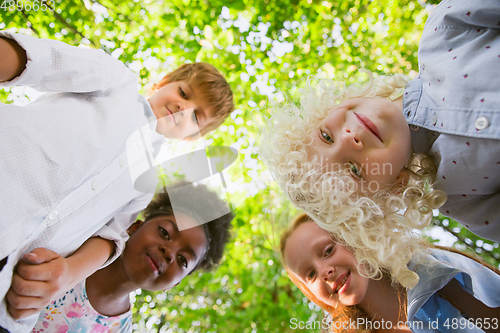 Image of Interracial group of kids, girls and boys playing together at the park in summer day