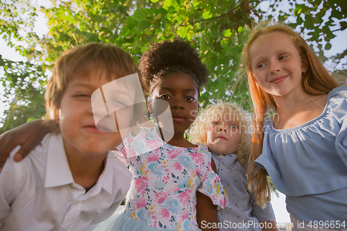 Image of Interracial group of kids, girls and boys playing together at the park in summer day