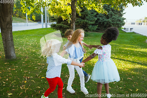 Image of Interracial group of kids, girls and boys playing together at the park in summer day