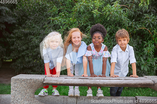 Image of Interracial group of kids, girls and boys playing together at the park in summer day