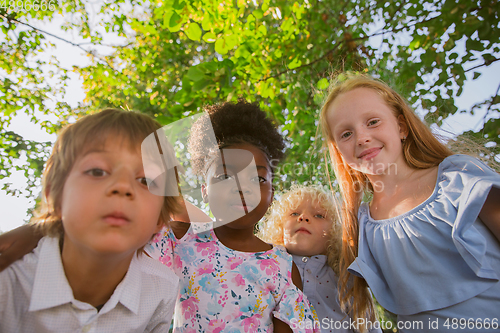 Image of Interracial group of kids, girls and boys playing together at the park in summer day