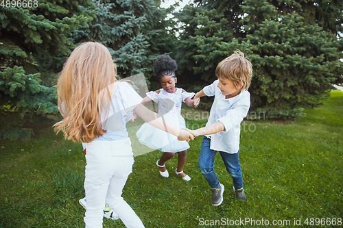 Image of Interracial group of kids, girls and boys playing together at the park in summer day