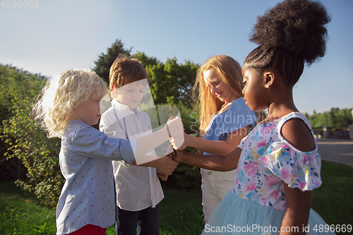 Image of Interracial group of kids, girls and boys playing together at the park in summer day