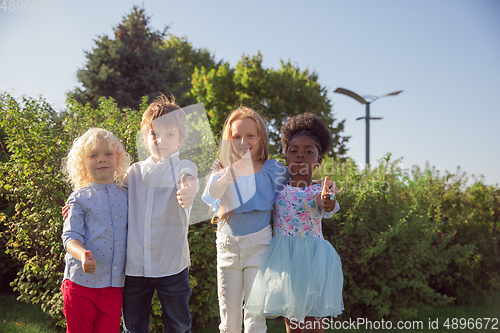 Image of Interracial group of kids, girls and boys playing together at the park in summer day