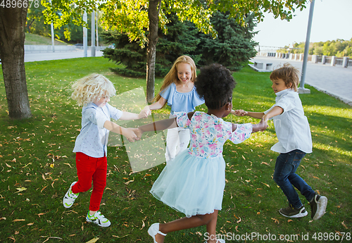 Image of Interracial group of kids, girls and boys playing together at the park in summer day