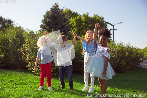 Image of Interracial group of kids, girls and boys playing together at the park in summer day