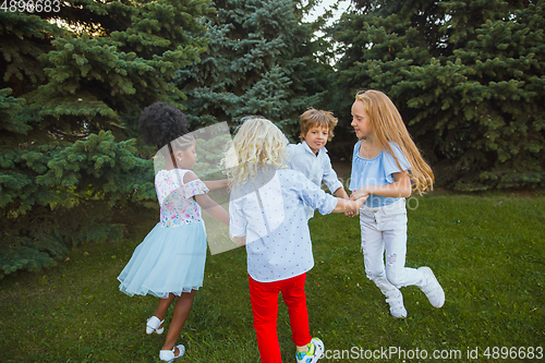 Image of Interracial group of kids, girls and boys playing together at the park in summer day