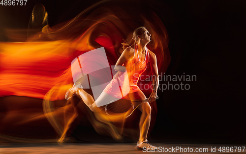 Image of Professional female tennis player isolated on black studio background in mixed light