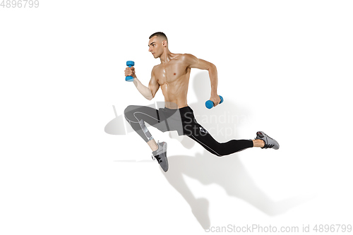 Image of Beautiful young male athlete practicing on white studio background with shadows