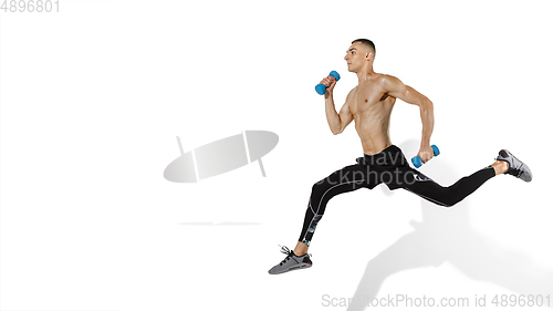 Image of Beautiful young male athlete practicing on white studio background with shadows