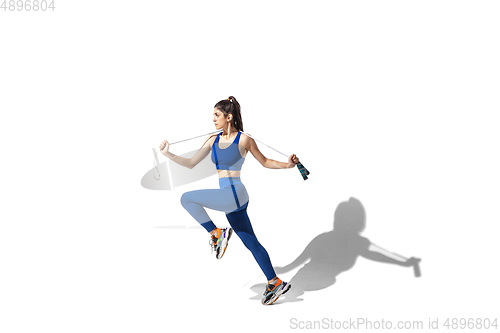 Image of Beautiful young female athlete practicing on white studio background with shadows