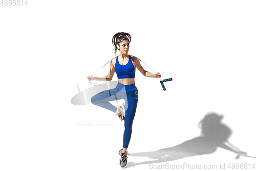 Image of Beautiful young female athlete practicing on white studio background with shadows