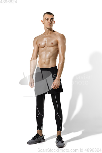 Image of Beautiful young male athlete practicing on white studio background with shadows