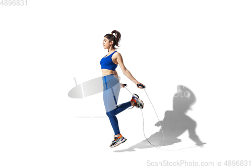 Image of Beautiful young female athlete practicing on white studio background with shadows