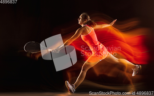 Image of Professional female tennis player isolated on black studio background in mixed light