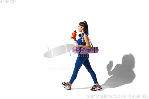 Image of Beautiful young female athlete practicing on white studio background with shadows