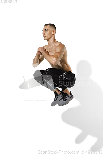 Image of Beautiful young male athlete practicing on white studio background with shadows