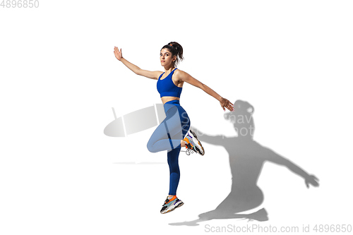 Image of Beautiful young female athlete practicing on white studio background with shadows